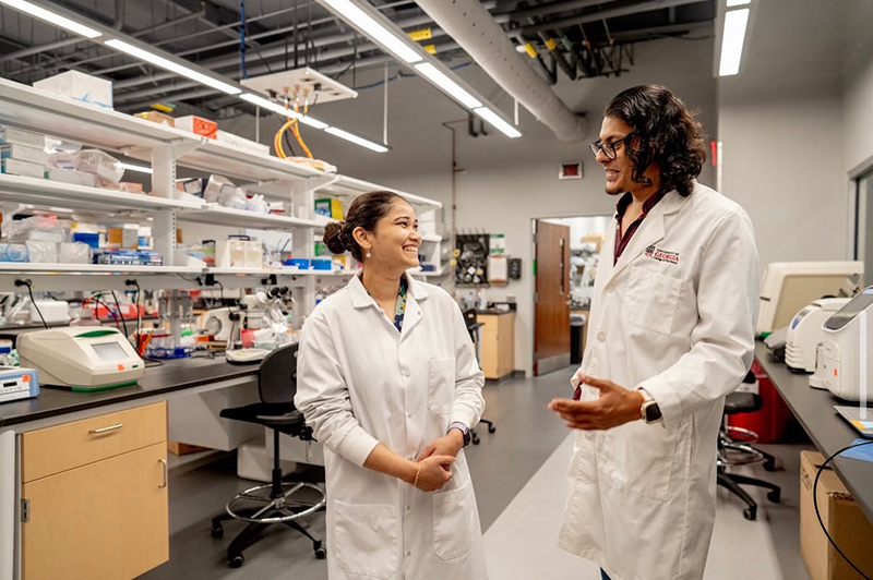 Siddhika Gamare and fellow graduate student talking in a lab setting