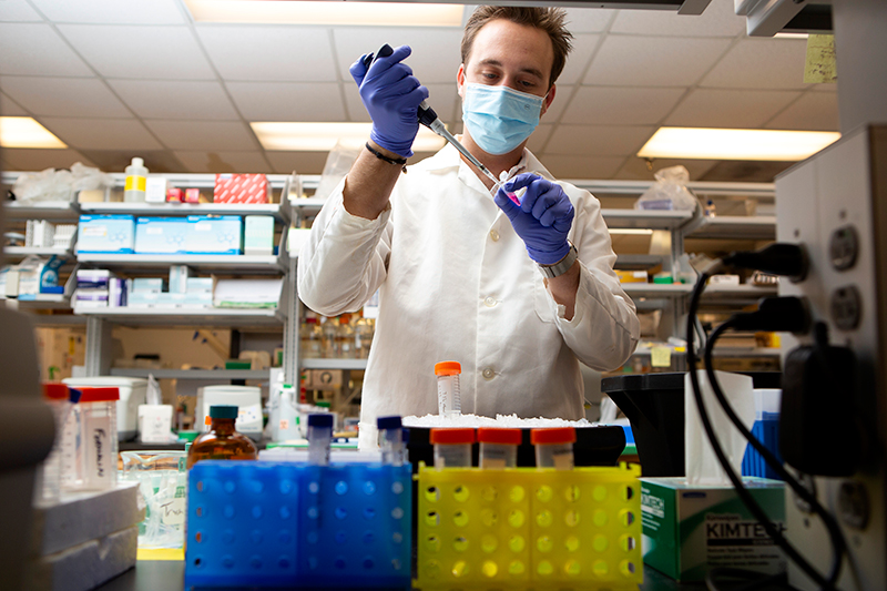Taylor Martin in mask and gloves working with lab equipment