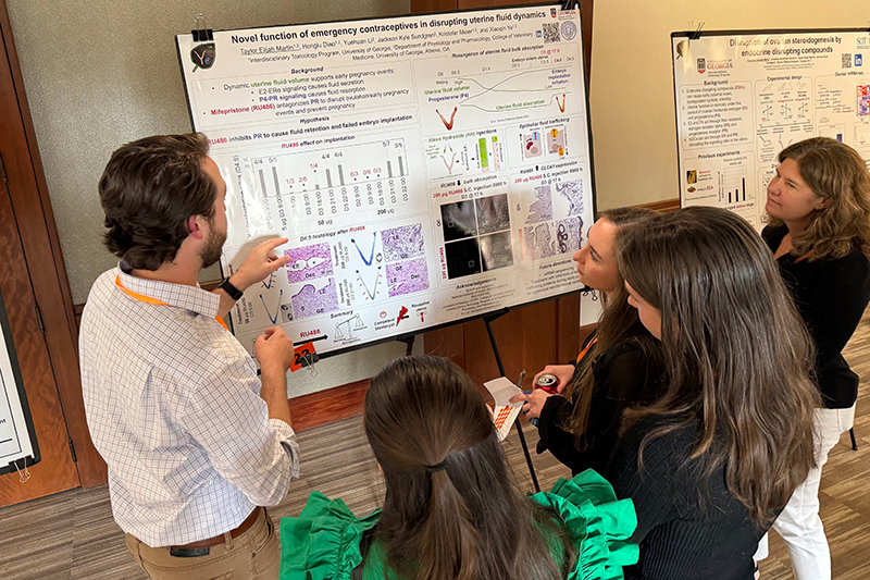 Taylor Martin discussing a poster with colleagues