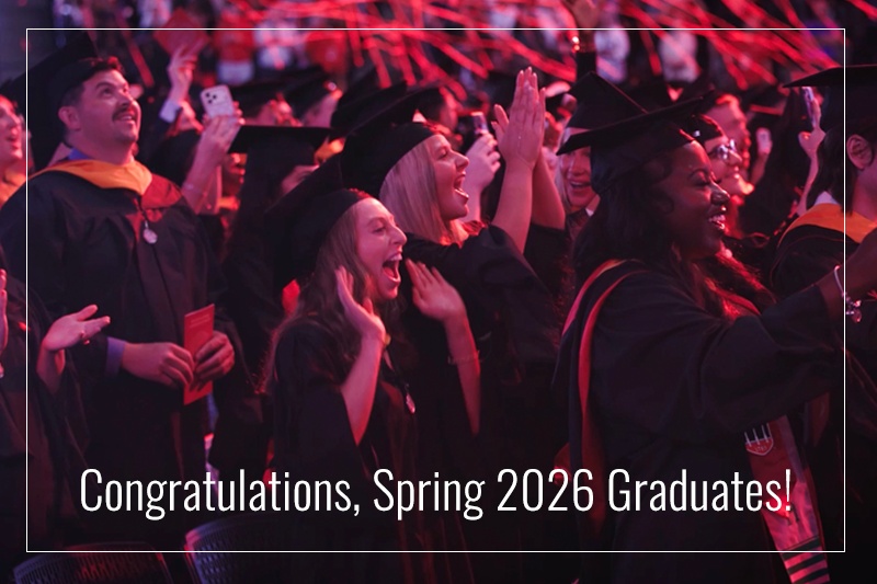 Graduate students celebrating Commencement in caps and gowns with streamers